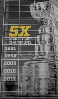 A large display features the image of the Stanley Cup and the text '5X Stanley Cup Champions' alongside the years 1991, 1992, 2009, 2016, and 2017. The display is on a glass building facade reflecting the environment, including a Lexus car and surrounding greenery.