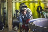 man welding a gray metal container