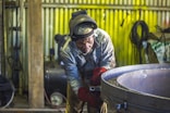 man welding a gray metal container