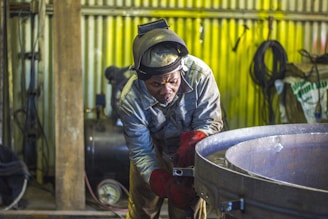 man welding a gray metal container