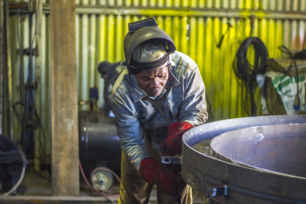 man welding a gray metal container