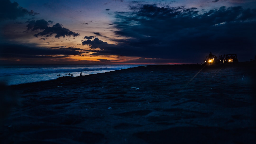 silhouette of person riding on car at the beach during dusk