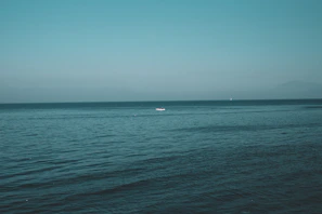 A serene ocean view with crystal-clear water and a small boat anchored near the shore