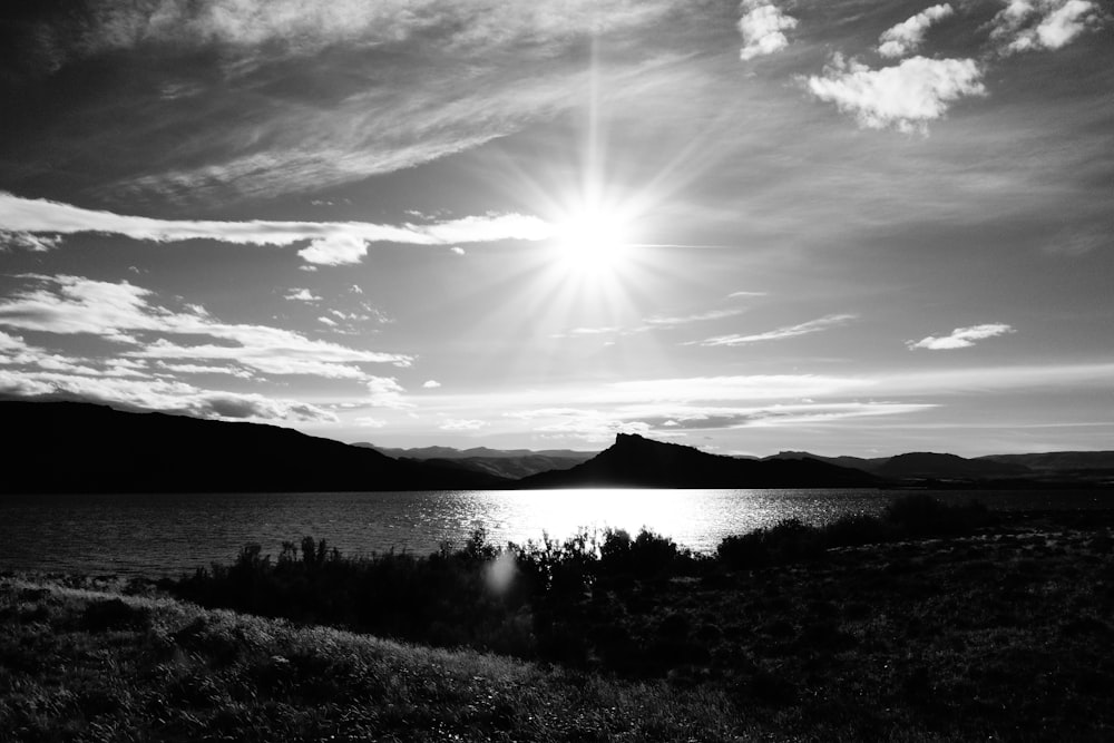 grayscale photography of body of water near mountain