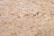 A close-up view of oriented strand board, showing an intricate pattern of compressed wood strands with a rough texture and varying shades of beige and brown.