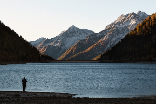 silhouette of person standing near body of water in Neves-Stausee Italy