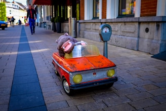 hippopotamus mascot riding red car toy beside the street