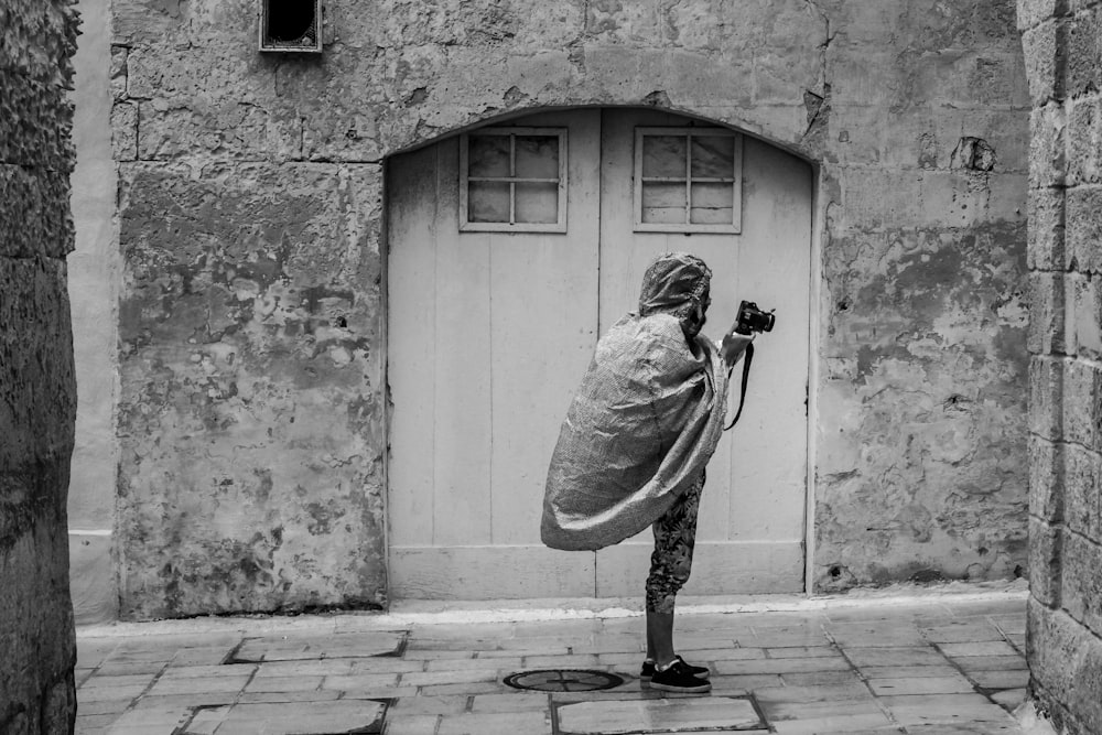 grayscale photo of person holding DSLR camera