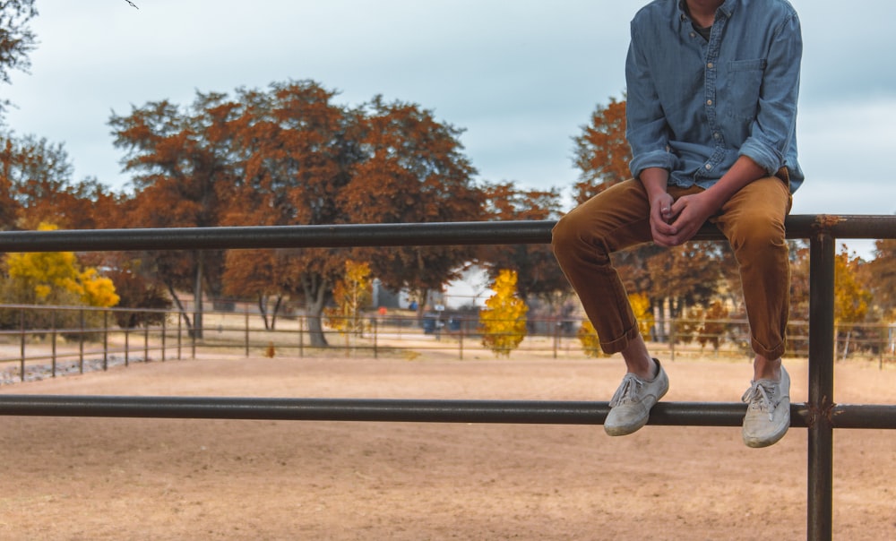 shallow focus photography of person sitting on rail way