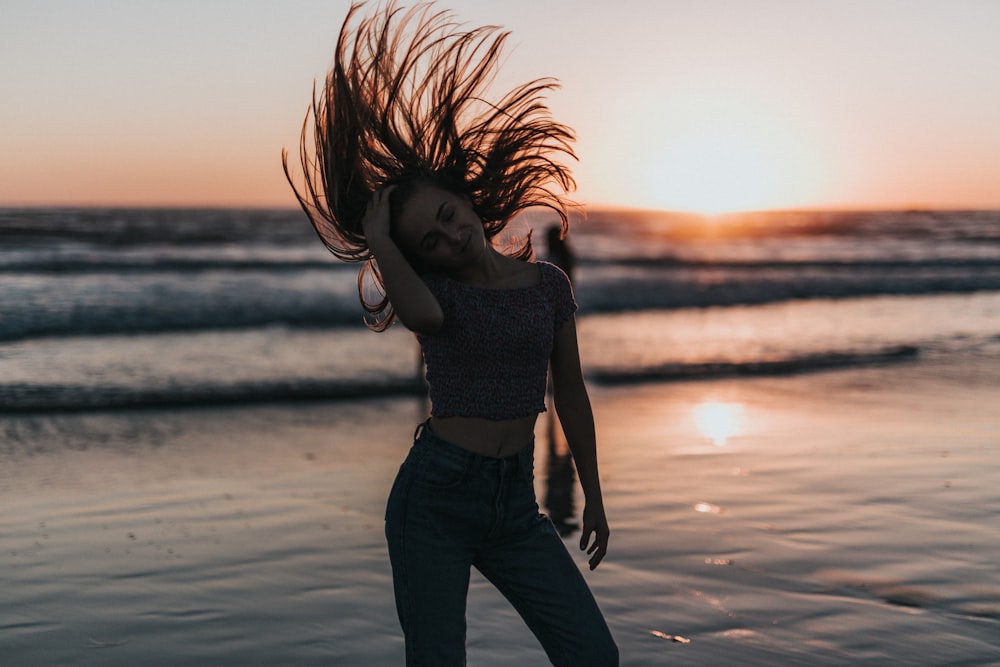 mulher virando o cabelo na praia durante o pôr do sol