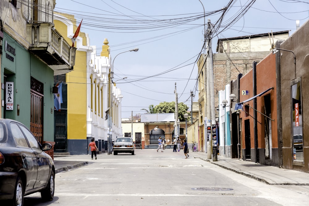 people waking in road between concrete buildings