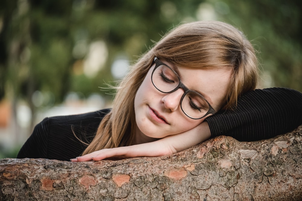 tilt shift photography of woman sleeping on log