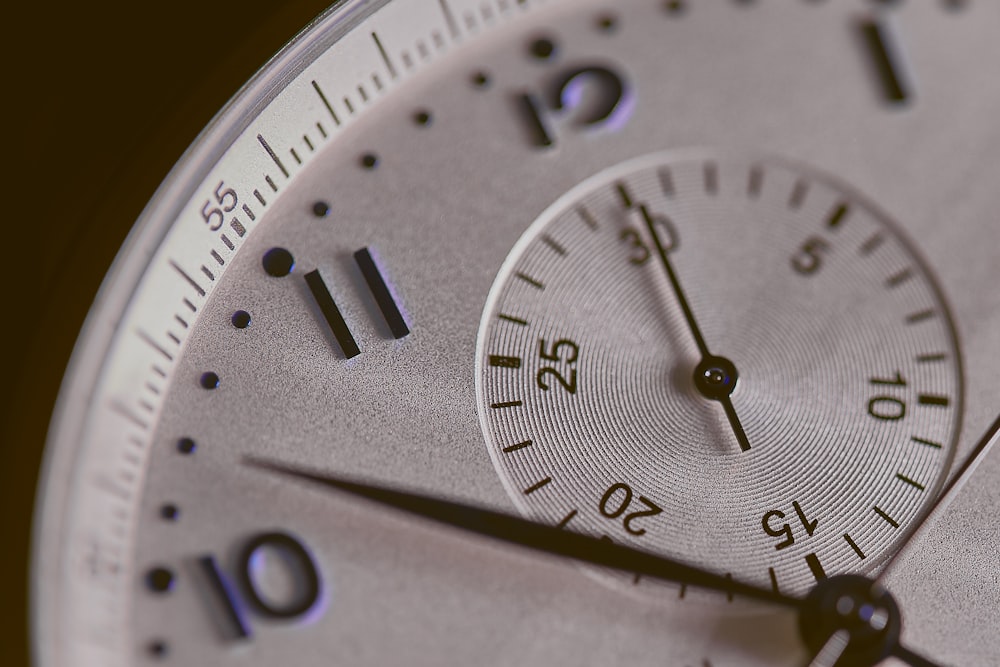 um close up de um mostrador de relógio prateado