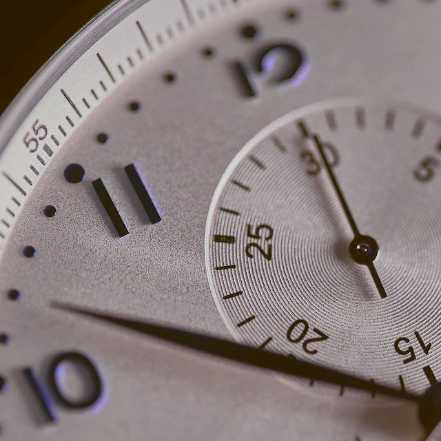 A close-up of a silver watch face with polished hands