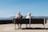 man and woman sitting on bench facing sea