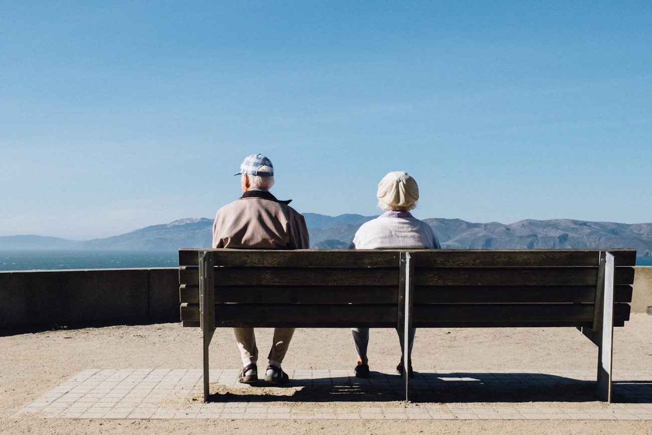 Casal de idosos sentado em um banco, contemplando o mar