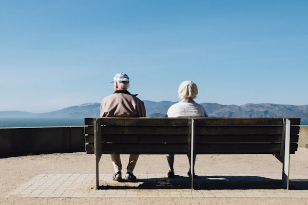 Mature couple sitting on a bench facing the sea
