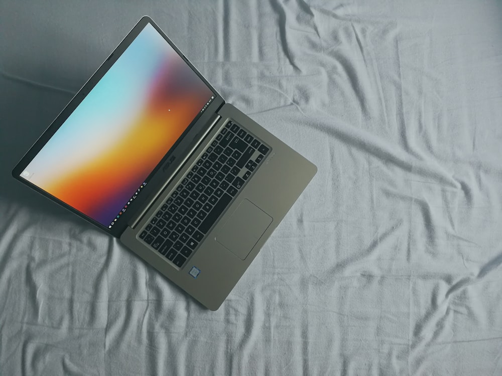 grauer Asus-Laptop auf weißem Bettlaken