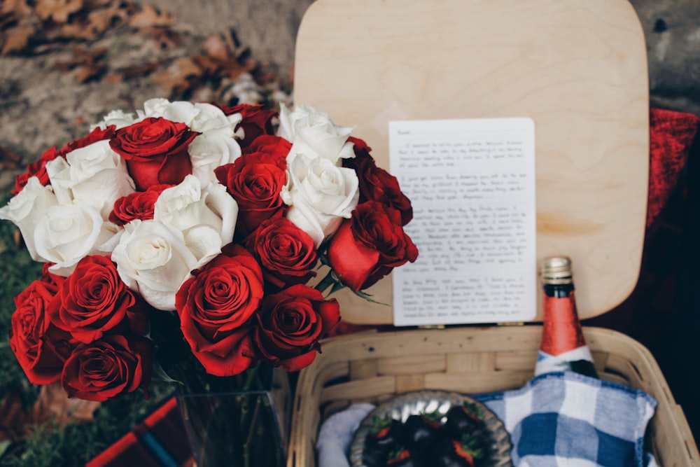 Rote und weiße Rosen neben beigefarbenem Weidenkorb