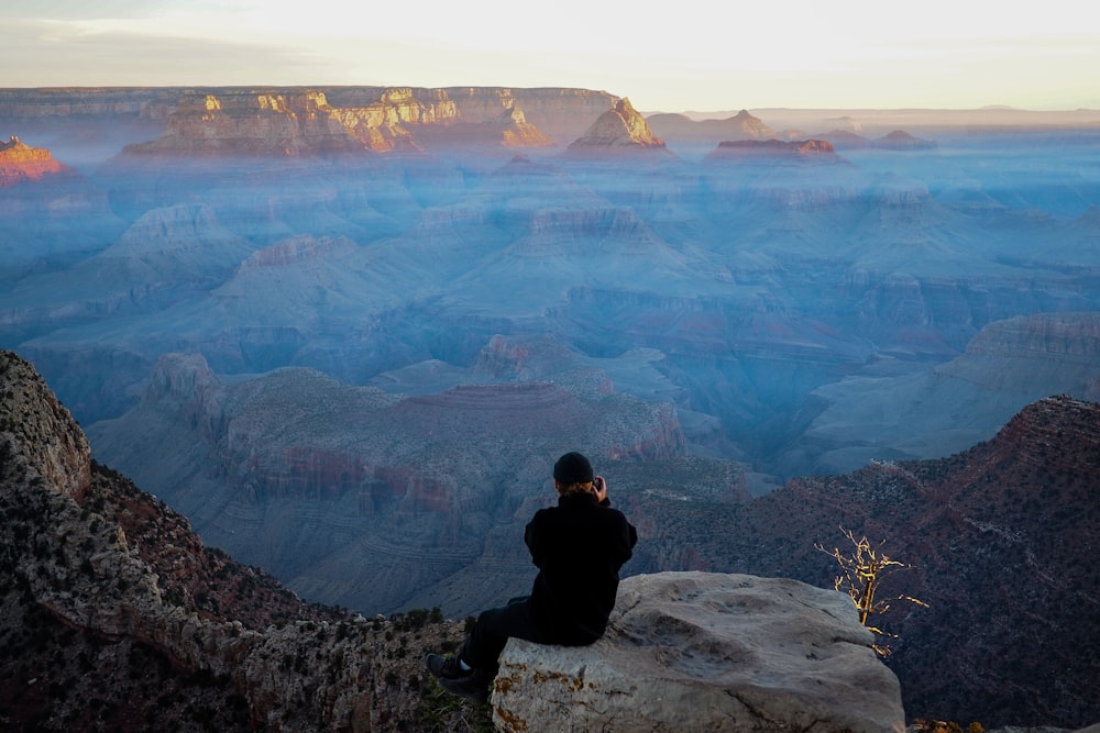 person sitting on rock cliff