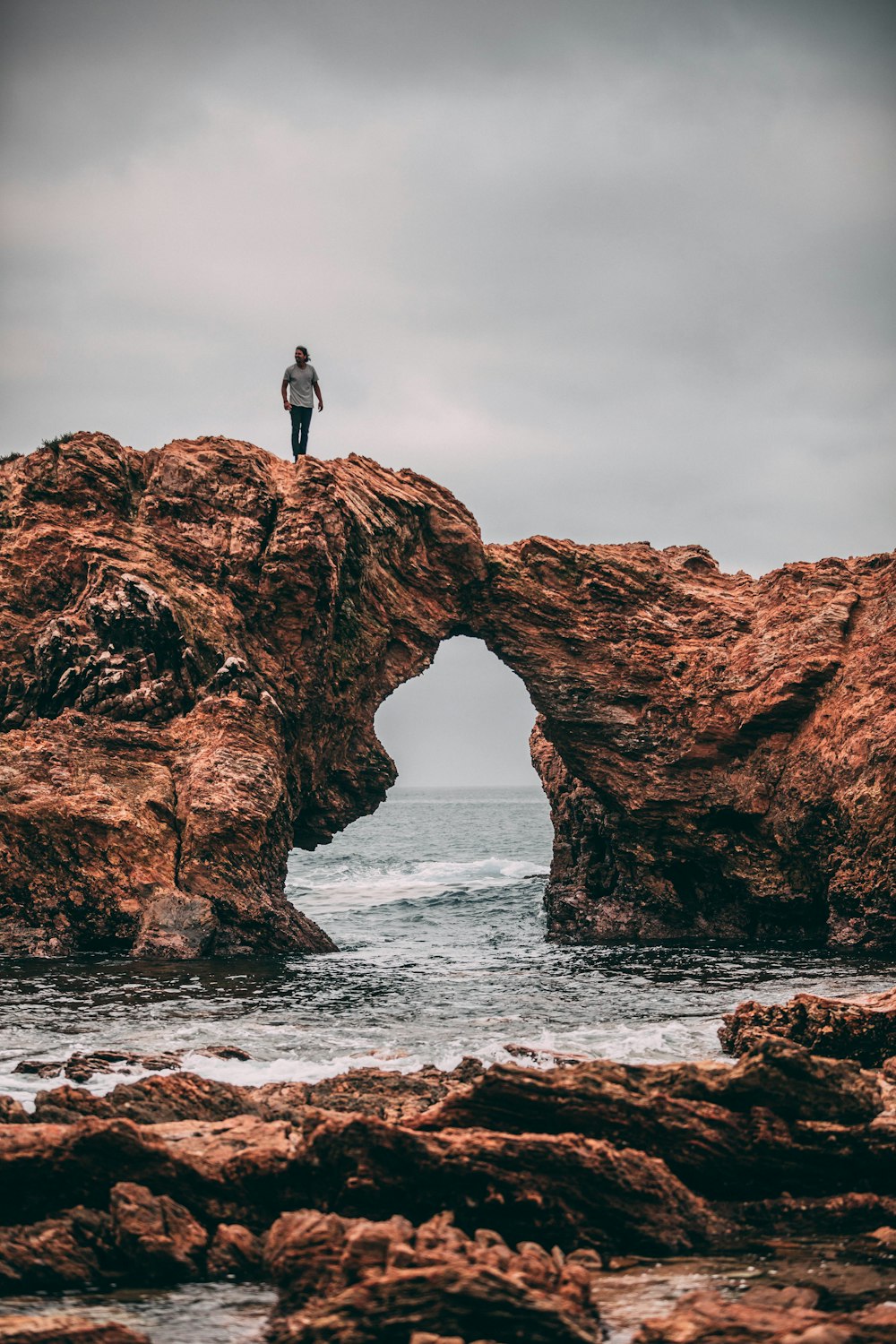 Fotografía de paisaje del hombre de pie en la cima de la colina de la montaña