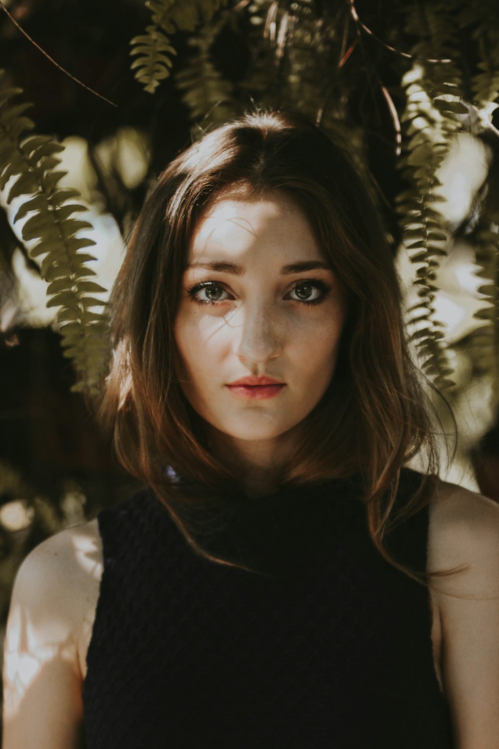 woman standing near fern plant