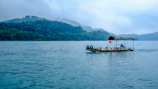Traditional boat gliding along the serene waters of Rangamati surrounded by rolling hills.