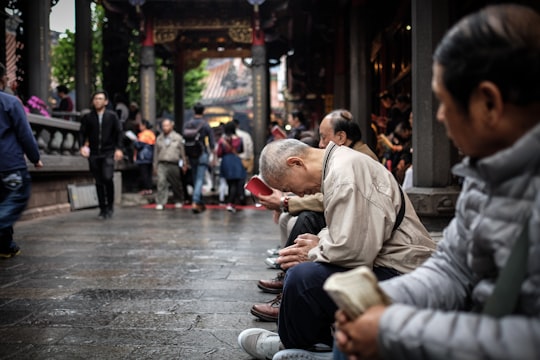 group of person sitting on chair in Lungshan Temple Taiwan