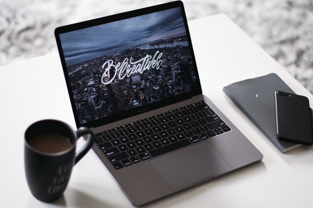 black and gray laptop computer beside black ceramic mug