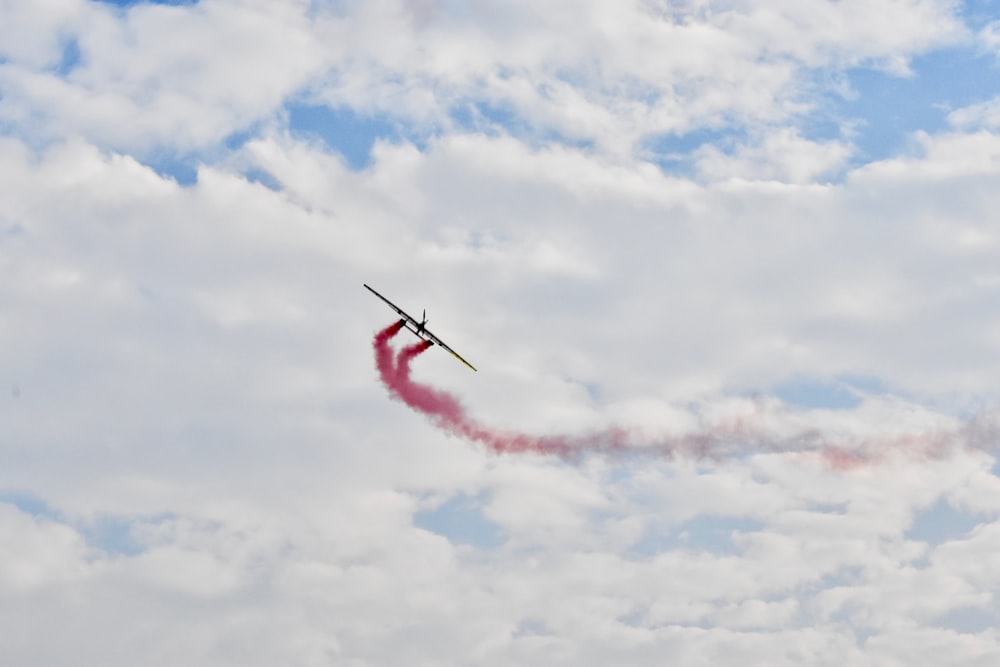 airplane releasing red smoke in mid air