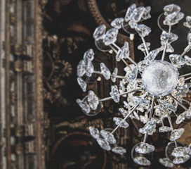 A sparkling neon-lit chandelier glowing with animated glitter effects against a dark backdrop.
