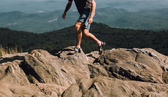 person in gray shirt walking on rocks in Black Balsam Knob United States