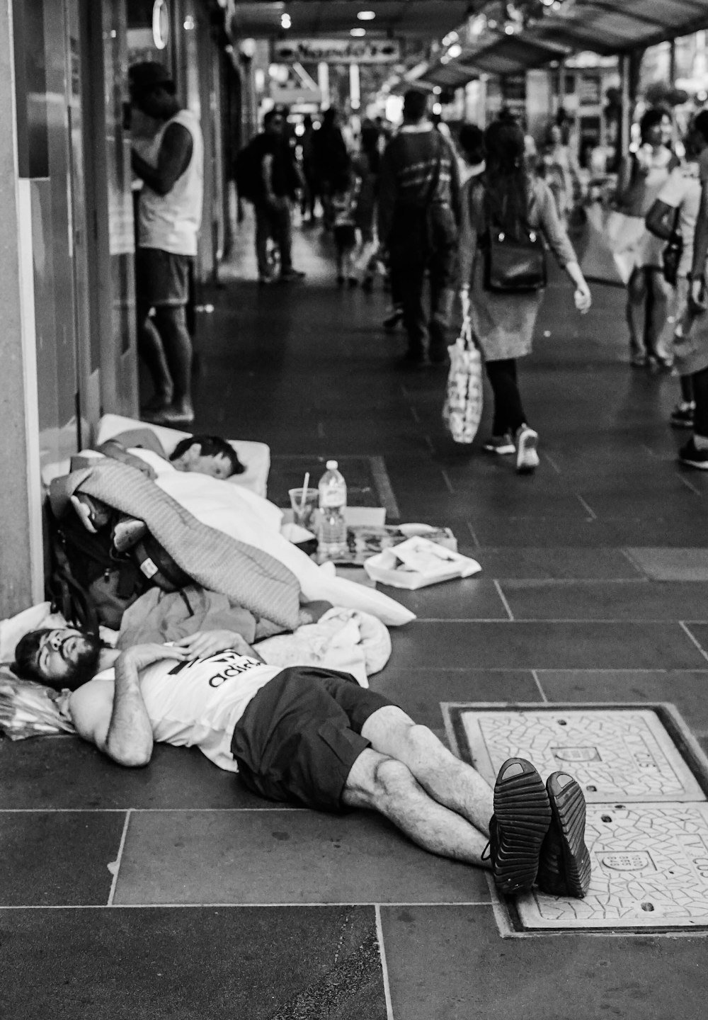 grayscale photo of man sleeping on street