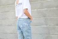woman in white shirt and blue denim bottoms facing the wall