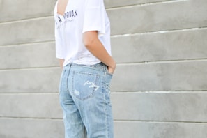 woman in white shirt and blue denim bottoms facing the wall
