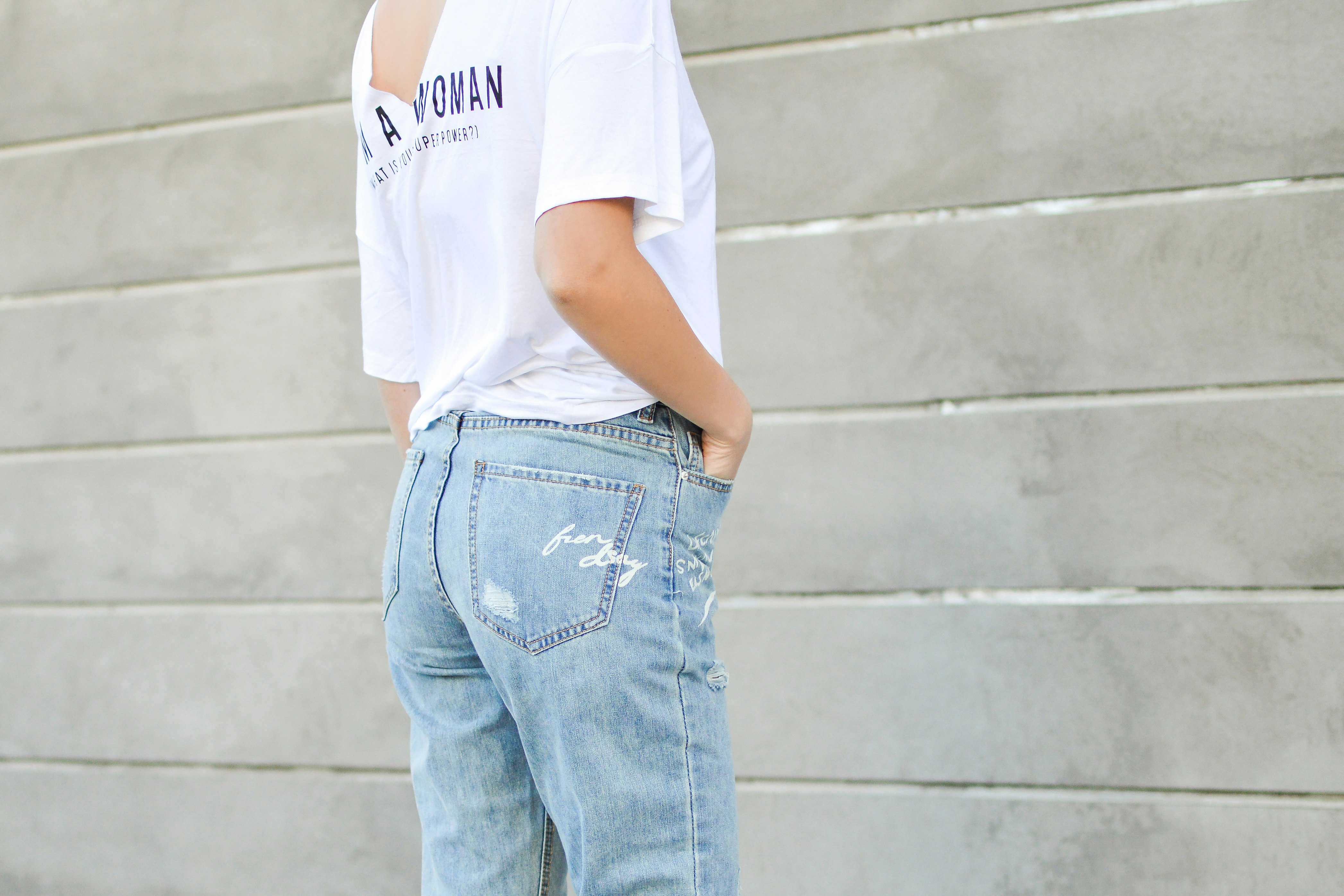 woman in white shirt and blue denim bottoms facing the wall