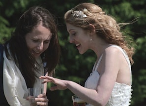 A candid moment of laughter between two women admiring their freshly done mehandi designs outdoors