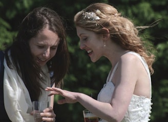 A candid moment of laughter between two women admiring their freshly done mehandi designs outdoors
