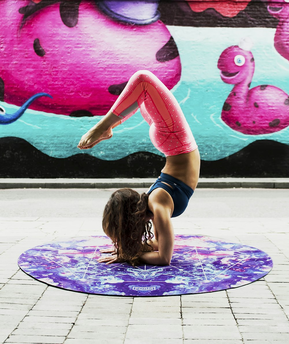 woman doing acrobats on purple mat during daytime