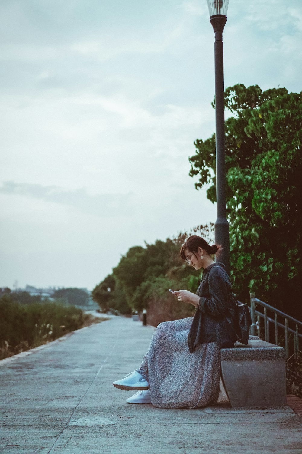 woman in on concrete chair while using mobile phone