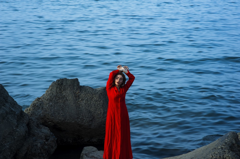 両手を頭の上に上げて石の上に立つ女性の浅い焦点写真