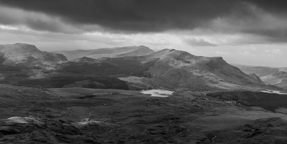 grayscale photo of mountains under clouds