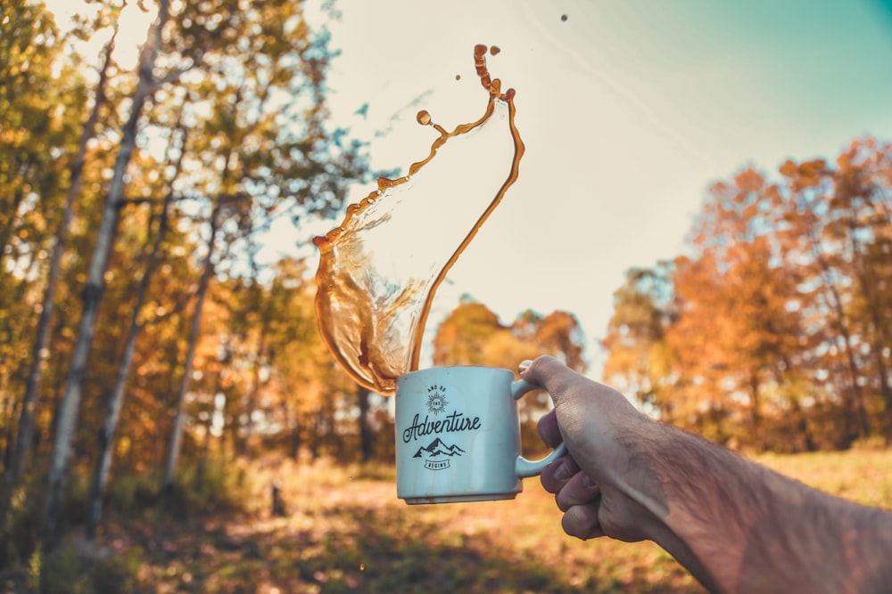 shallow focus photography of person spilling coffee from mug