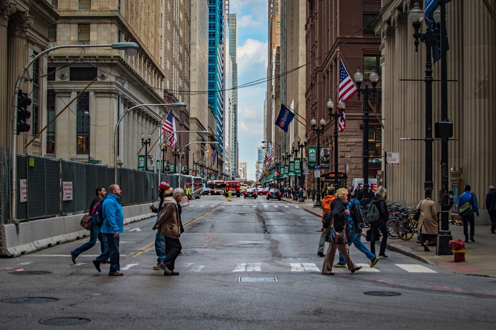 people crossing on pedestrian lane near buildings during daytime