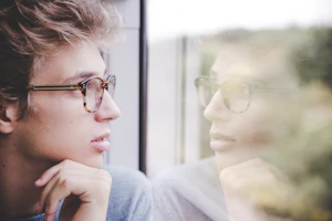 A man looking thoughtfully out of a window
