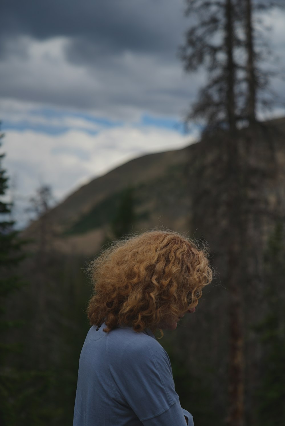 woman looking downward near trees