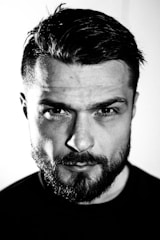 A powerful, close-up portrait of a confident man against a textured dark background, embodying strength and focus.