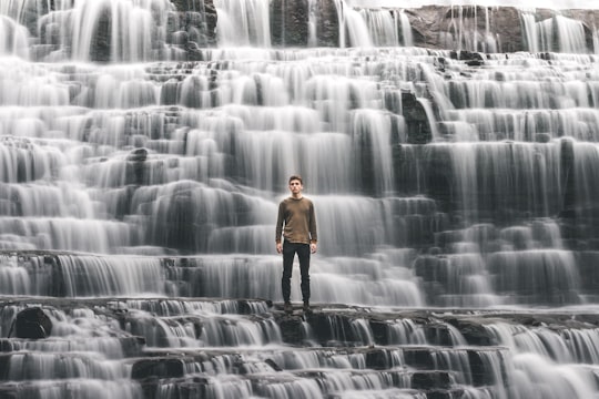 man standing on waterfalls in Albion Falls Canada