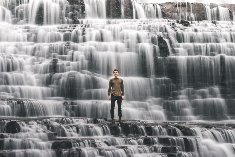 man standing on waterfalls
