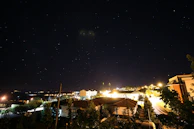 Nighttime view of Ibirité city lights glowing warmly with a clear starry sky above.